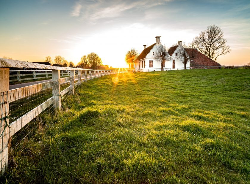 Beautiful shot of a fence leading to a house in a green grass area